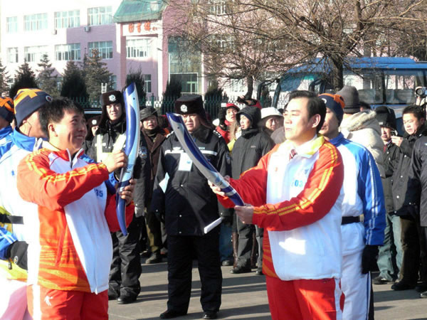 黑龙江三江美术职业学院院长王英海教授（右）将圣火交给北京奥运会火炬手蔡世良