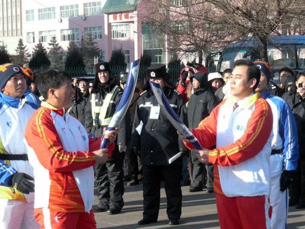 黑龙江三江美术职业学院院长王英海教授（右）将圣火交给北京奥运会火炬手蔡世良